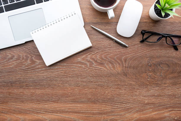 istock Wood office desk table with blank notebook, laptop computer and office supplies. Top view with copy space, flat lay. 1253065840