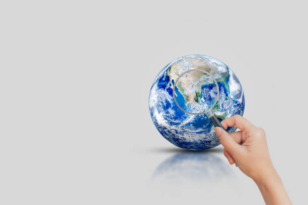 istock Hand holding magnifying glass to look at blue planet earth. 1253067170