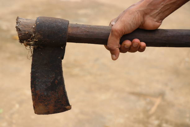 istock Very old and rusty axe with wooden handle held in hand 1253070557
