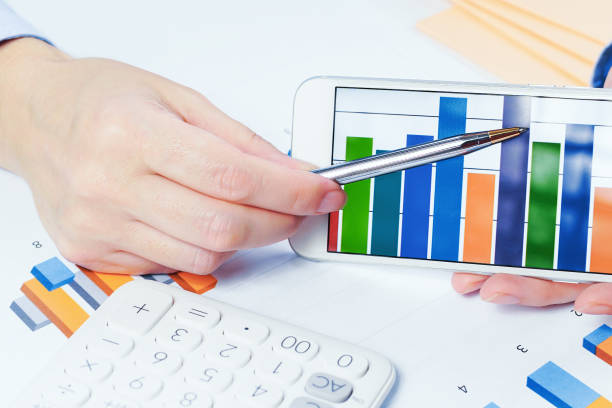istock Finance. Female hand with calculator on financial graphs on desk 1253070600
