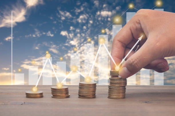 istock saving money hand putting coins on a stack on a table with graph and arrow up 1253071531