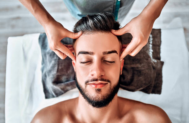 Handsome man having head massage in spa salon