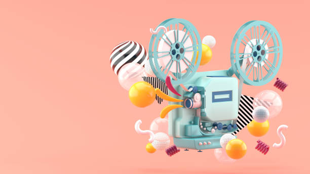 istock Blue movie projector amid colorful balls on pink background.-3d render. 1253073384