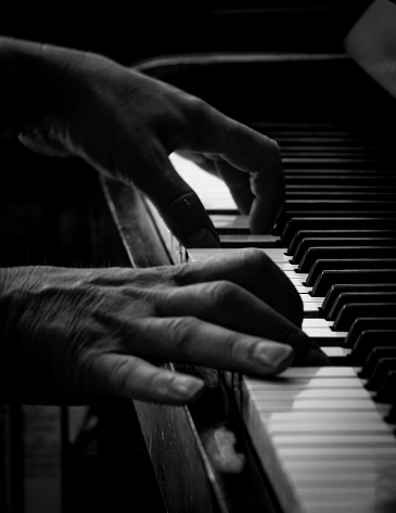 Black and white image of a person playing an old piano