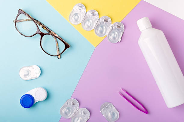 istock Contact lens kit with bottle of lens solution, case, tweezer on multicolor background, copy space, top view 1253076151