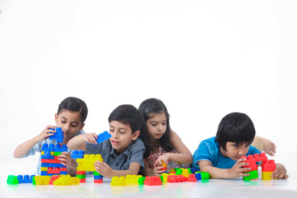 istock Kids Playing With Toy Blocks Against White Background laying on front 1253077548