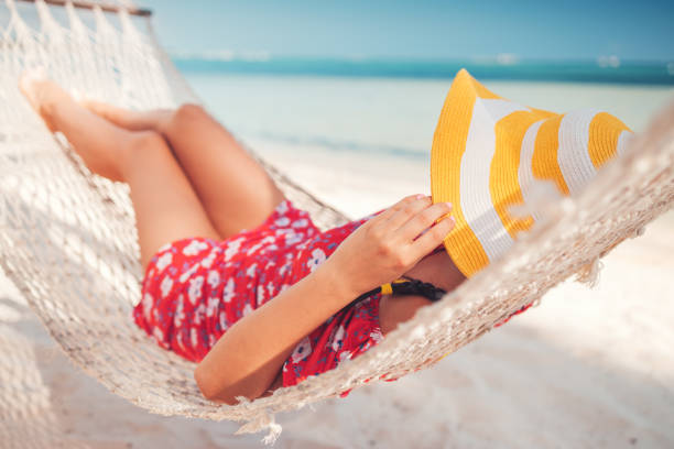 istock Young girl resting in a hammock under tall palm trees, tropical beach 1253077989