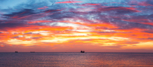 istock Sun setting at the sea with sailing cargo ship, scenic view 1253078802