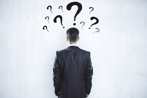 Businessman looking on blank wall with question mark over head. Business and challenge concept.