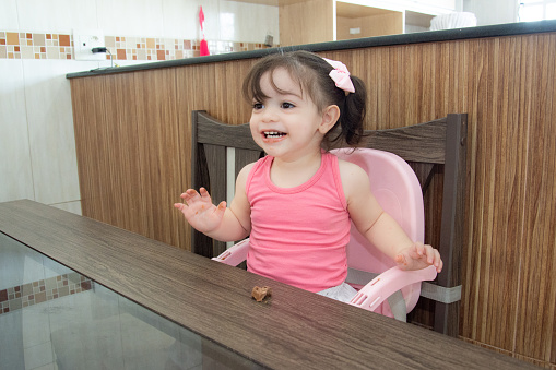 baby girl at kitchen table eating chocolate