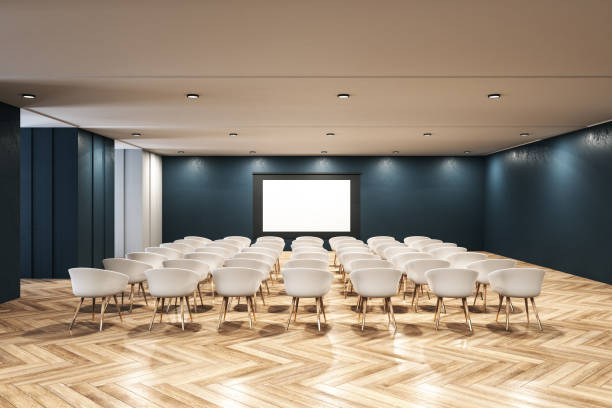 istock Minimalistic interior of a presentation room with white chairs and blank screen 1253082577