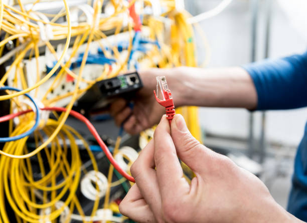 istock Network engineer working in server room. Connecting network cables to switches 1253084619