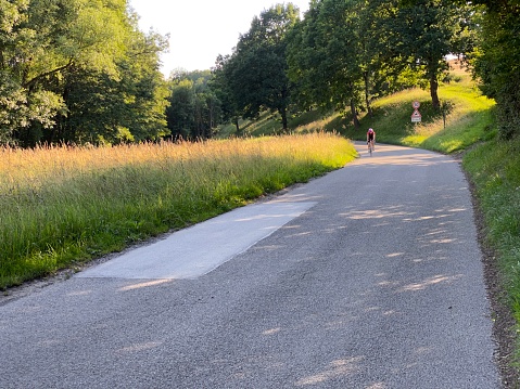 Steinheim, Germany - June, 21 - 2020: Country road at sunset. In the background a female biker arriving.