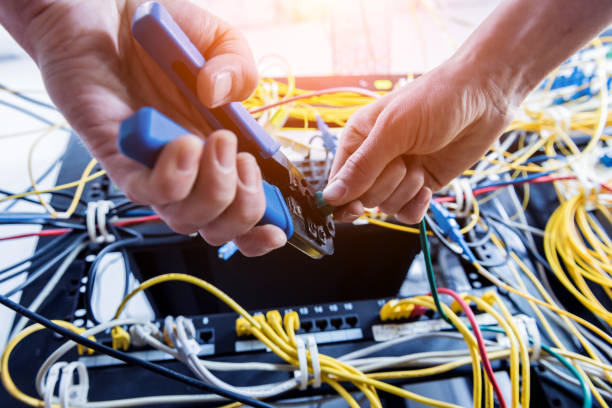 istock Network engineer working in server room. Connecting network cables to switches 1253085052