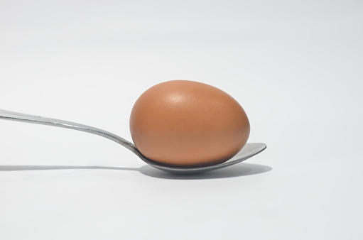 Silver Spoon with brown egg in isolated white background