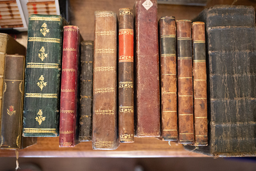 Piles of books in an old library, detail of side covers.