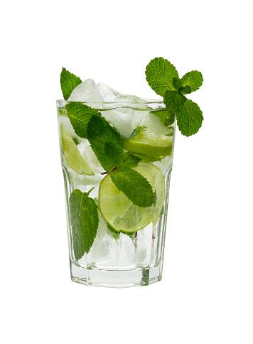 Close up one full big glass of mojito cocktail with mint leaves, lime slices and ice cubes, isolated on white background, low angle side view