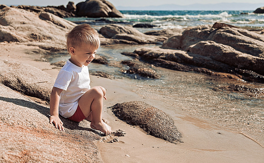 Happy baby boy having fun at the beach