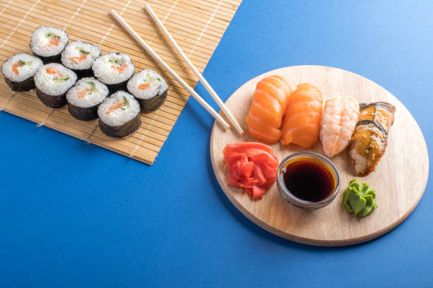 sushi-rollen set auf holzbrett serviert - chopsticks soybean japanese cuisine blue stock-fotos und bilder