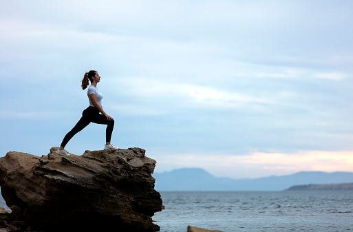 a woman doing yoga on the rock on a beach