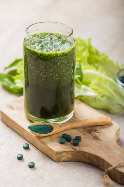 grüner smoothie mit spirulina. junge gerste und chlorella spirulina. detox superfood. - barley wheat grass green stock-fotos und bilder