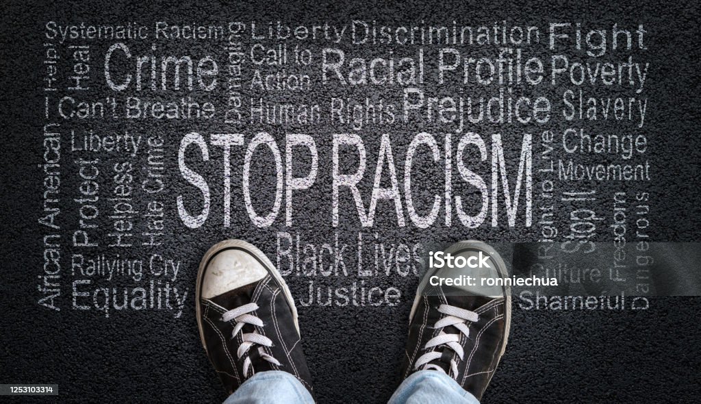 Stop Racism Word Cloud on Asphalt Concept of Fighting Discrimination Person standing over Stop Racism word cloud. Concept of stopping discrimination against blacks or people of color because their lives matter. Anti-racism Stock Photo