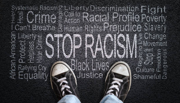 Stop Racism Word Cloud on Asphalt Concept of Fighting Discrimination Person standing over Stop Racism word cloud. Concept of stopping discrimination against blacks or people of color because their lives matter. social justice concept photos stock pictures, royalty-free photos & images
