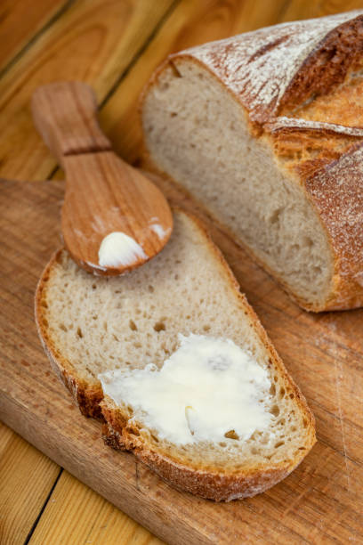 istock Butter spreading on fresh bread. Bread in the home kitchen. Dark background. 1253110987