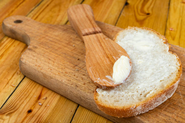 istock Butter spreading on fresh bread. Bread in the home kitchen. Dark background. 1253111002