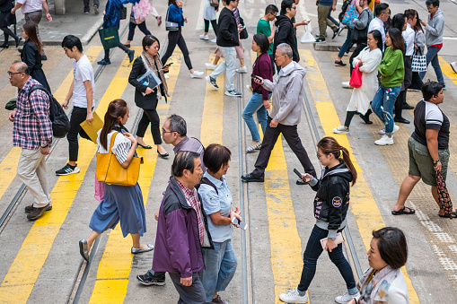 HongKong, China - November, 2019: People crossing street in crowded shopping district of HongKong City