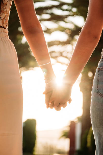 istock Young lesbian couple holding hands walking at sunset 1253119201