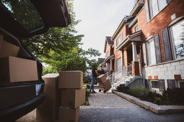istock Young man carrying boxes from the car into the house 1253119345