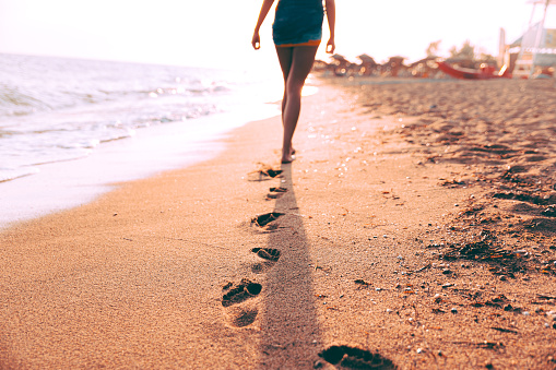 Woman walking on the sand and leaves footprints