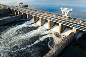 Dam with flowing water through gates. Hydroelectric power station, aerial top view
