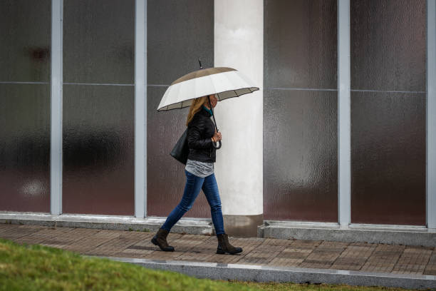 fashionabla женщина в маске и ходить с зонтиком в дождь - wall women leather street стоковые фото и изображения