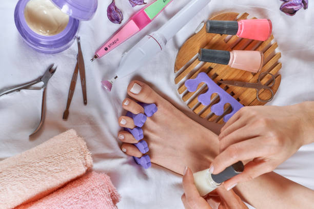 Applying pedicure to woman's feet with white toenails, with toe separators Applying pedicure to woman's feet with white toenails, with toe separators home pedicure stock pictures, royalty-free photos & images