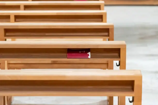 Red hymnbook under the prayer kneeling table in the church