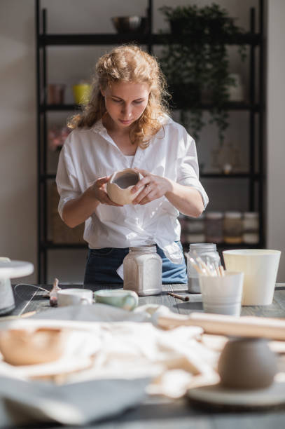 istock Female potter glazing raw unburned ceramic cup using brush. Earthenware mug putting colorant on pottery workshop 1253130406