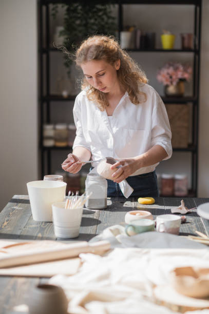 istock Close up of a woman making ceramic and pottery tableware at the workshop, working with clay and glaze 1253130412