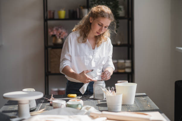 istock Close up of a woman making ceramic and pottery tableware at the workshop, working with clay and glaze 1253130415
