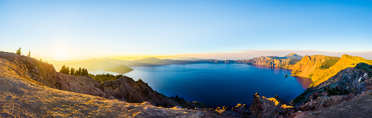 Panorama view of a volcano crater lake at sunset, with forest slopes and still water in a natural park in Oregon, United States