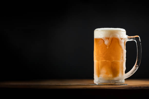 istock cold mug with beer, with overflowing foam, on wooden 1253143747