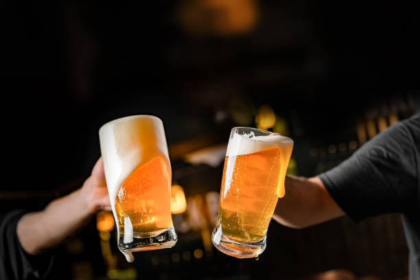 istock two hands with beer mugs, toasting in celebration, with overflowing foam 1253144451