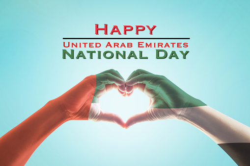 UAE, United Arab Emirate national day with flag pattern on people's hands in heart shape on blue mint sky background