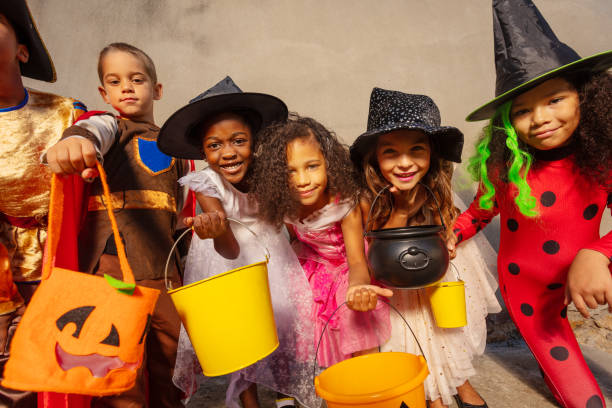 Halloween kids group together with candy buckets Many kids hold Halloween candy buckets and smile looking to the camera trick or treat photos stock pictures, royalty-free photos & images