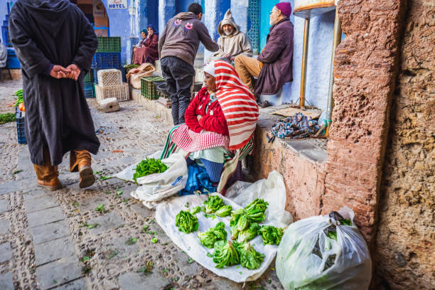 Morocco attractions editorial Local woman sells vegetables at the famous blue city of Chefchaouen, Morocco. Chefchaouen, Morocco - April 11 2016. moroccan girl stock pictures, royalty-free photos & images