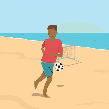 boy with red shirt playing with soccer ball and goal on a sandy beach near the ocean