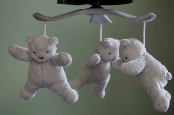 Three plush teddy bears hanging from a baby mobile