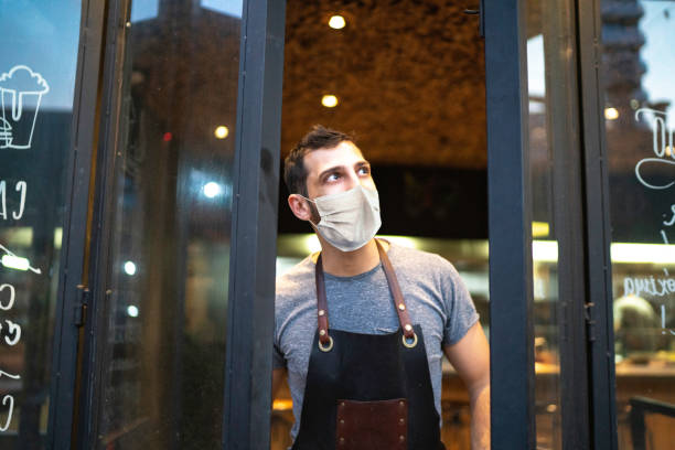 istock Small business owner closing front door with face mask 1253158663