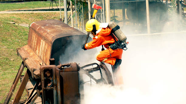istock Firefighter fighting with flame using fire hose chemical water foam spray engine. Fireman wear hard hat, body safe suit uniform for protection. Rescue training in fire fighting extinguisher 1253165563